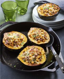 A halved acorn squash filled with quinoa, chickpeas, and apricots, showcasing its vibrant colors and hearty filling.