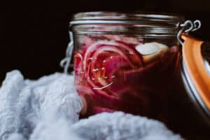 A jar of vibrant spicy pickled red onions, showcasing their bright color and tangy appearance.