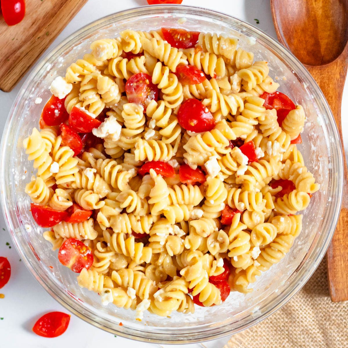 4 Ingredient Pasta Salad in a serving bowl topped with tomatoes, cheese, and dressing.