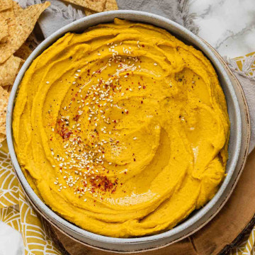 Yellow-orange hummus in a bowl.