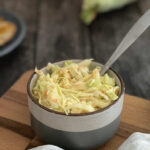 Spoon resting in a bowl of fresh homemade coleslaw.