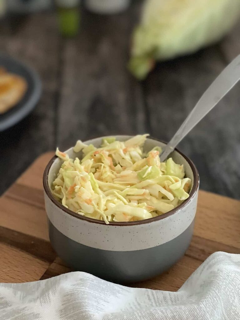 Spoon resting in a bowl of fresh homemade coleslaw.