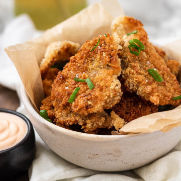 Golden brown breaded and fried mushrooms in a bowl.