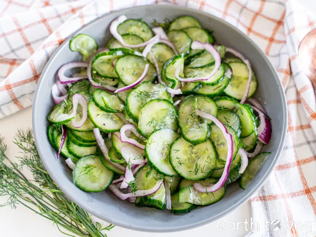 German cucumber salad with red onions and vinegar served in a bowl. 