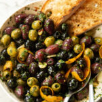 Close-up shot of a variety of olives in a bowl, showcasing different colors and sizes