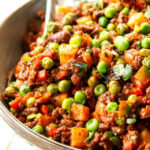 A close-up of a serving spoon in a bowl of Mexican Picadillo, ready to be served